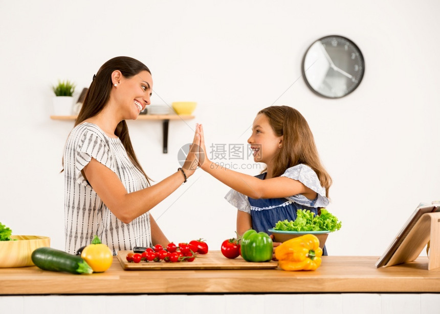 白种人拉丁裔家庭母亲和女儿在厨房玩得开心的一图片