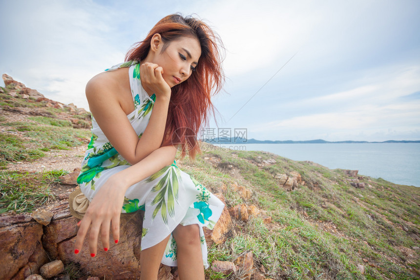 美丽亚洲人年轻的女坐在山地和海边的悬崖上在山顶和海边登者图片