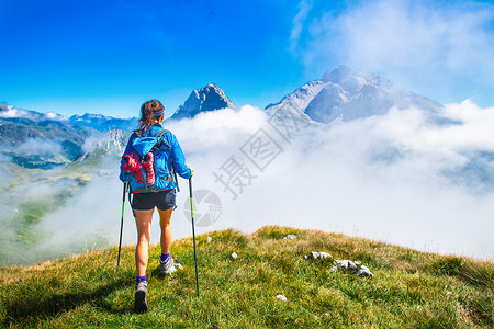 背包假期一个女孩在山上用棍棒爬的时候全景图片
