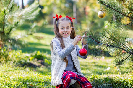 户外装饰圣诞树的可爱女孩图片