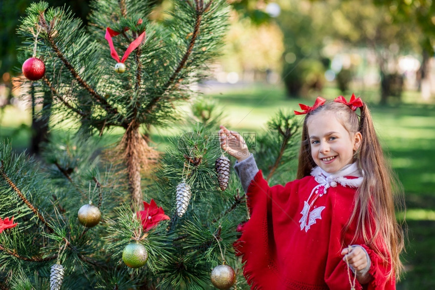 院子里装饰圣诞树的可爱女孩图片