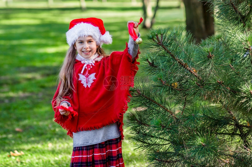 院子里装饰圣诞树的小女孩图片