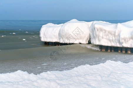 雪浪海浪在冰冷的雪泥中在海的防波堤上结冰在冬天的海岸中防波堤上冰在冷雪泥中海浪在冬天岸白色景力量背景