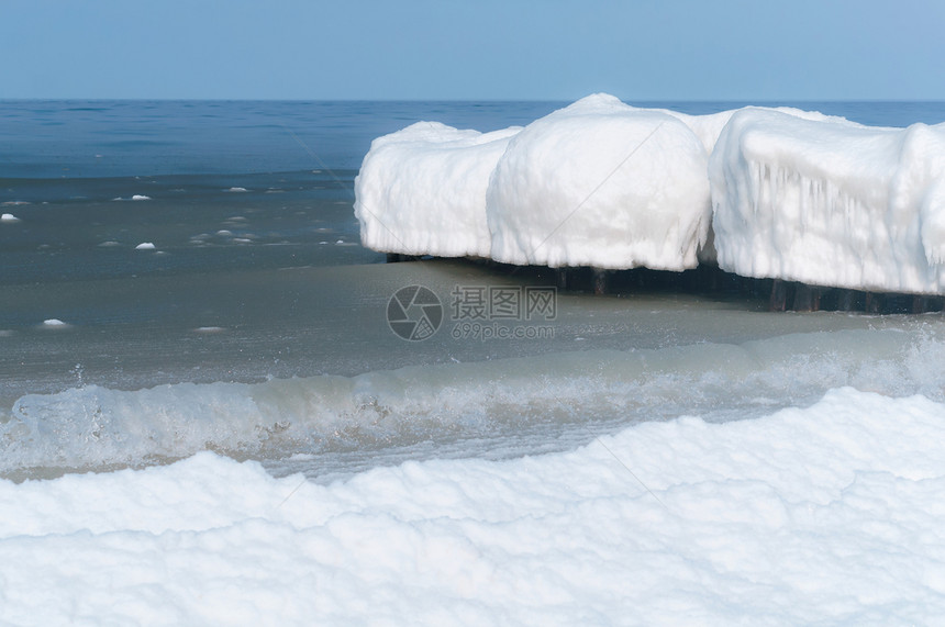 假期欧洲海浪在冰冷的雪泥中在海的防波堤上结冰在冬天的海岸中防波堤上冰在冷雪泥中海浪在冬天岸木制图片