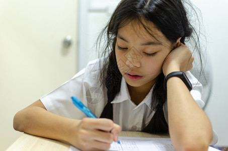 制服身着校的美丽亚洲年轻女孩想在餐桌上做家庭作业故意的学习图片