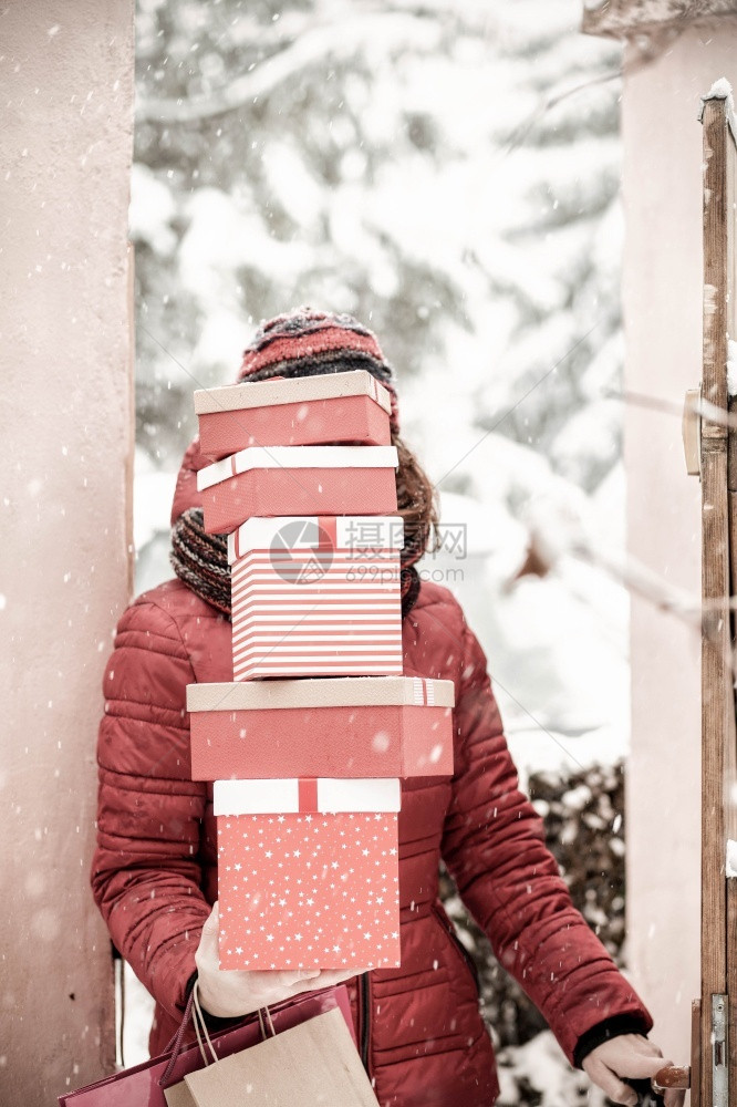 手冬天妇女从购物后回家时拿着成堆的圣诞礼物箱幻想图片