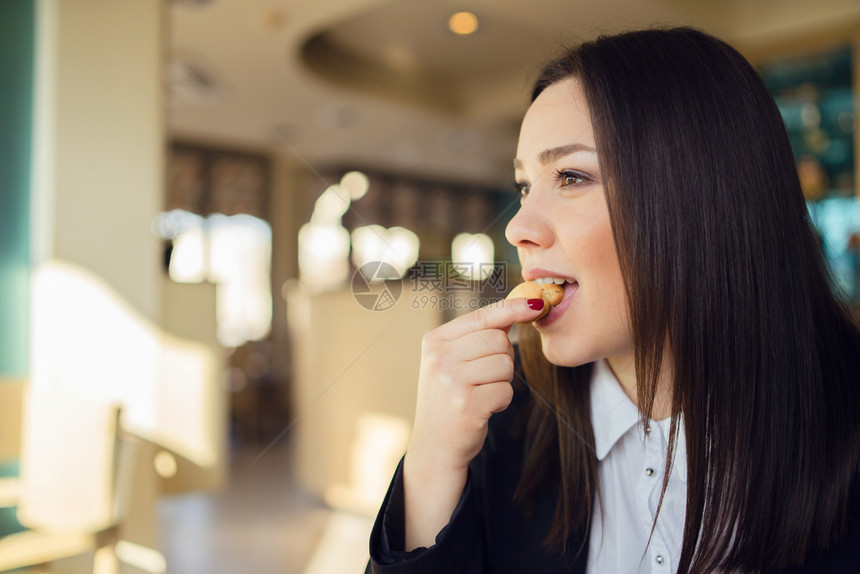 在刹车时坐咖啡馆或办公室餐桌旁吃饼干的年轻女子肖像制动早餐坐着图片