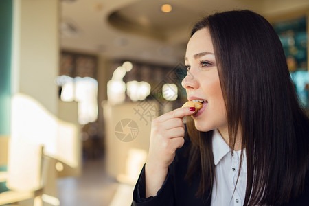 在刹车时坐咖啡馆或办公室餐桌旁吃饼干的年轻女子肖像制动早餐坐着图片