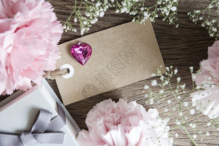老的满天星带礼品盒和木背景的康乃馨花空白纸标签色的图片