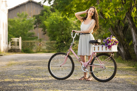 裙子放松一个美丽的年轻女子骑着自行车满是野花女孩图片