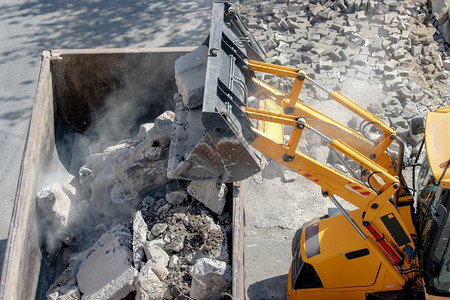 废墟路面灰尘将混凝土碎片上载到建筑工地倾卸卡车的推土机装载图片