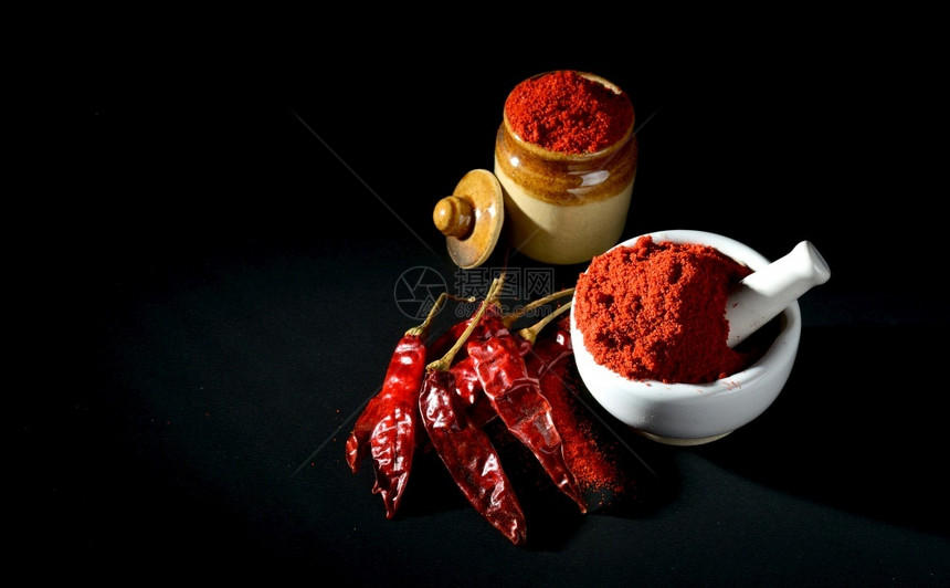 红辣椒粉用迫击和粘土锅粉碎黑色底有红辣椒粉几内亚自然末图片