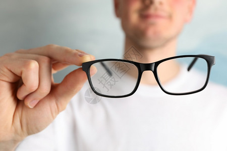 光学的医生穿TT衬衫的年轻人拿着眼镜关上配饰图片
