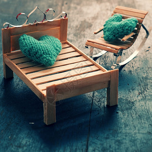 两颗心要在一起情侣像插图一样相爱照顾和护绿色心放在手工制作的迷你家具上作为椅子摇摆在木本底床上坐着长椅木制的背景图片