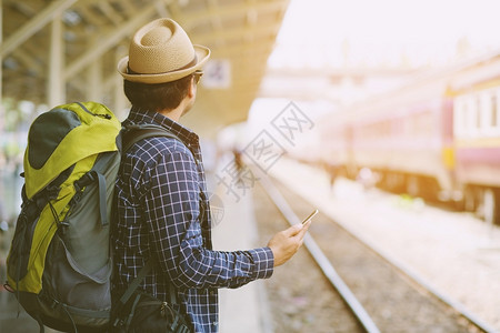 男人平台年轻子旅行者带着戴墨镜背包和帽子在上等待火车的旅游概念城市图片