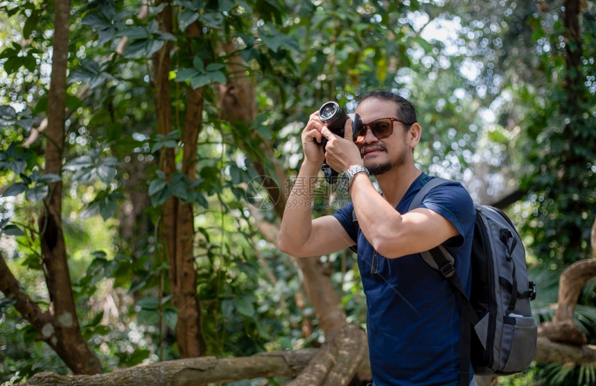 步行亚洲男子背包和旅行者一起走在欢乐地森林上拍照假期概念旅行时间较慢相机技术图片