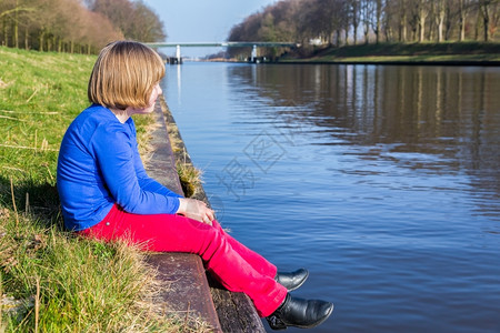 红色的银行运河坐在滨水边享受风景的年轻女孩图片