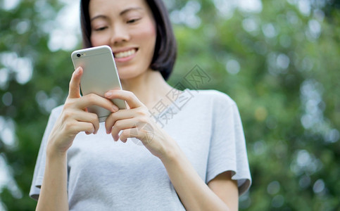 草数字的妇女在公园里使用移动智能手机女士图片