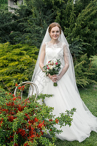 吸引人的穿着白礼服迷人新娘花束在园女孩面纱图片
