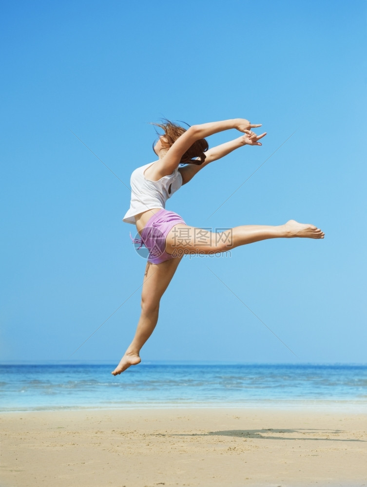 旅行玩海洋美丽的精力充沛年轻女子在海滩上跳跃图片