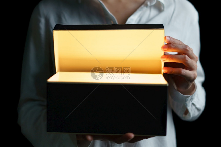 夜晚女人开一个金光的盒子里面有令人兴奋的东西礼物微笑图片