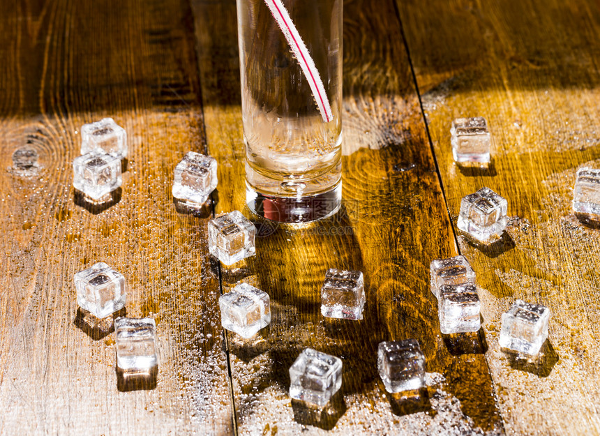 蓝色的寒冷融化透明冰立方体和一杯加鸡尾酒的苏打汽水熔化透明冷冰的立方体和一杯加鸡尾酒的苏打液体图片