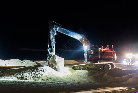 动人的舀机械土方工程夜间在黑暗中工作的地面人用挖掘机将沙移到海滩进行维护在夜间工作设计图片