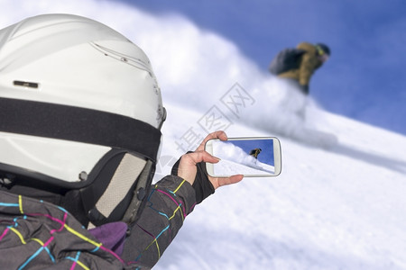 顺风车一名年轻女孩用手机拍下山上滑雪搭便车驾驶员的照片景观跳线年轻的背景