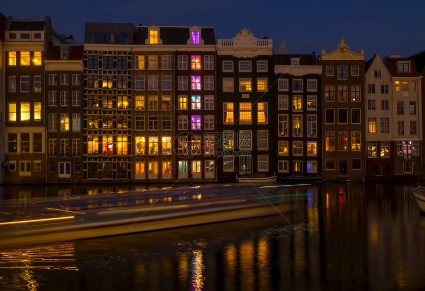 发光的历史夜在阿姆斯特丹的荷兰古典运河和在夜间阿姆斯特丹运河上动屋和船只的一艘建筑物图片