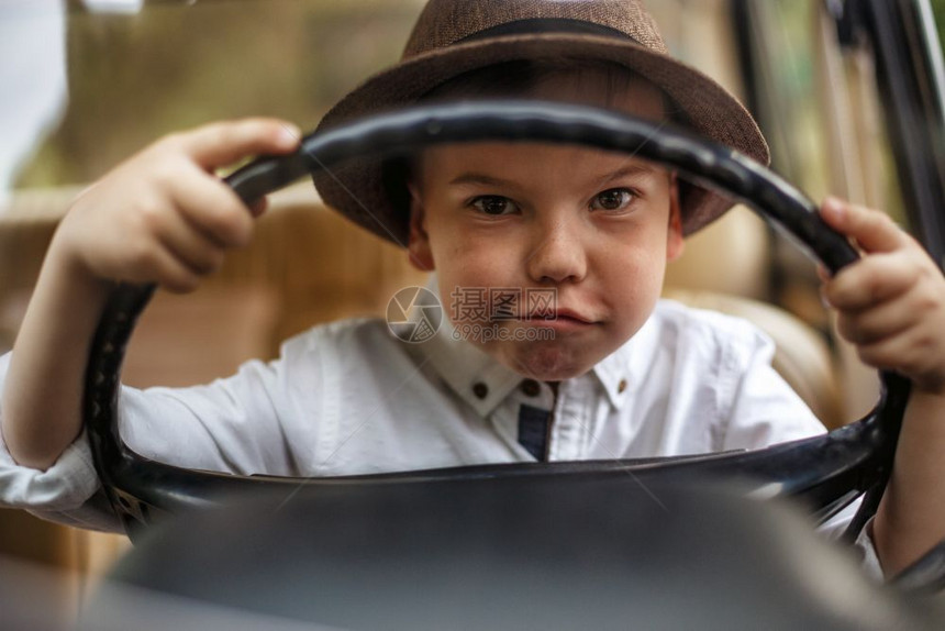 一种驾驶古董穿着老衣服的白人小男孩坐在一辆旧车里图片