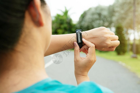 健身女运动员在开展户外锻炼活动前设置智能手表运动合身的齿轮图片