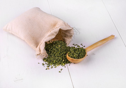 棕色的草本植物白厨房桌上的一小袋加干绿色香料和木勺子白色的图片