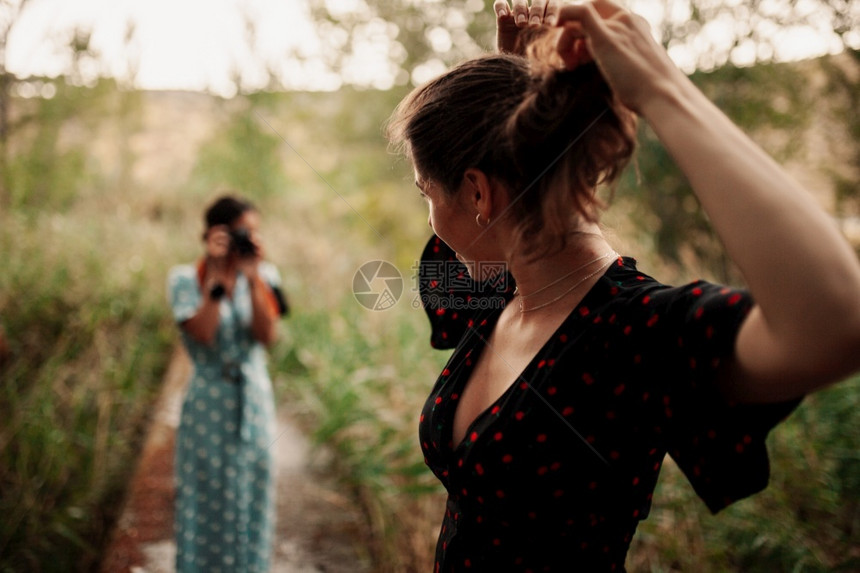 女领口两个年轻女子在森林里拍相照在穿着衣服的树丛中相机图片