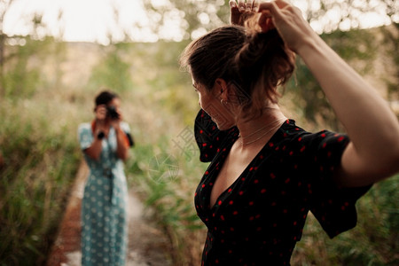 女领口两个年轻女子在森林里拍相照在穿着衣服的树丛中相机背景图片
