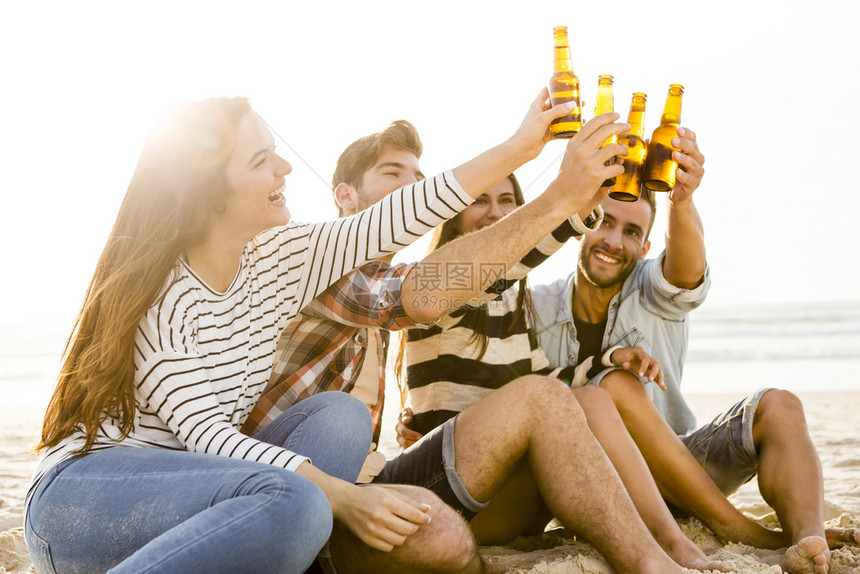女男人朋友在沙滩玩得开心喝冷啤酒的年轻图片