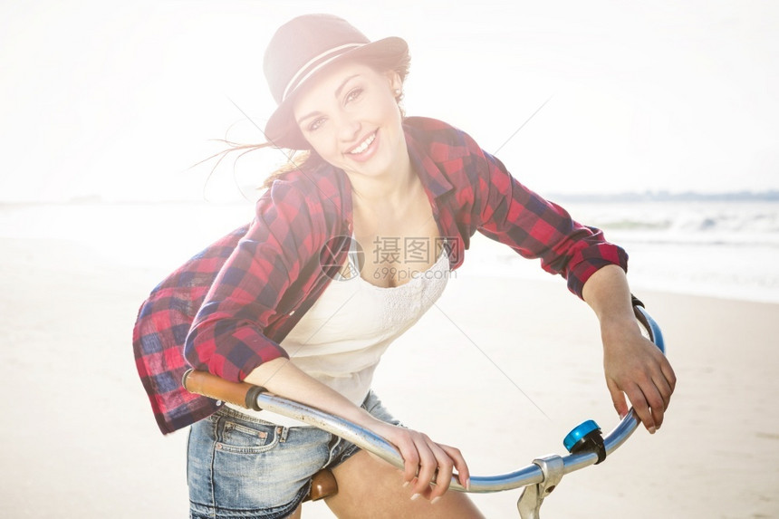 潮人一个有魅力的年轻女子在海滩上骑着自行车美丽漂亮的图片