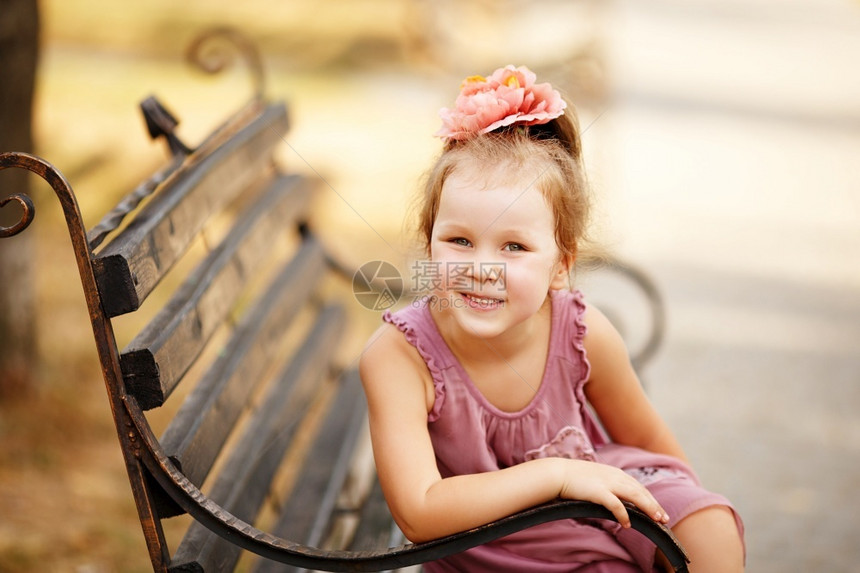 坐在公园长椅上一个笑着的漂亮小女孩肖像微笑快乐漂亮图片