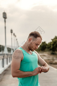 小工具男在慢跑之后或前看健身追踪器读数的白种人T恤肖像画成图片