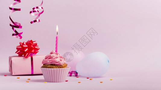 新鲜的星在粉红背景下配着生日快乐蜡烛的纸杯蛋糕丰富多彩的图片