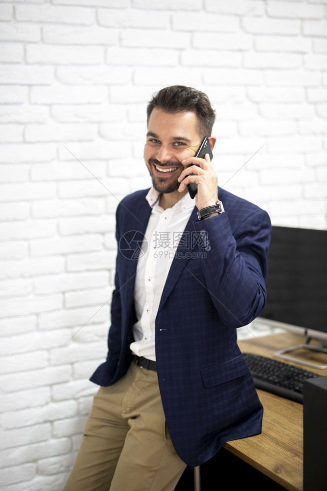 英俊男子讲电话脑喜悦办公室图片