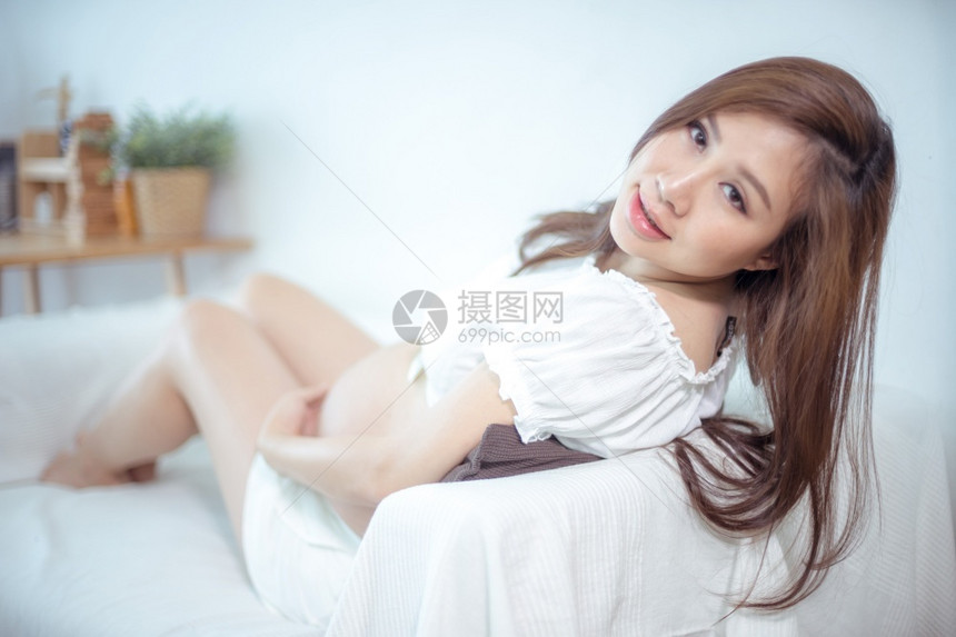 有吸引力的怀孕亚洲妇女躺在床上抱着肚子微笑女白色的图片