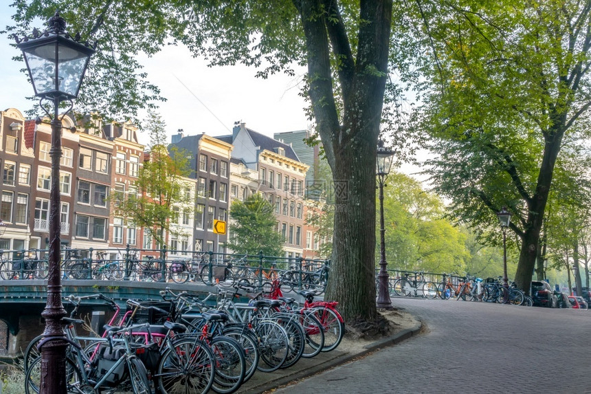 车轮老的早晨荷兰在阿姆斯特丹运河的上午有许多自行车停在桥上以及阿姆斯特丹运河银行的公园式双轮车停在桥和堤岸上图片