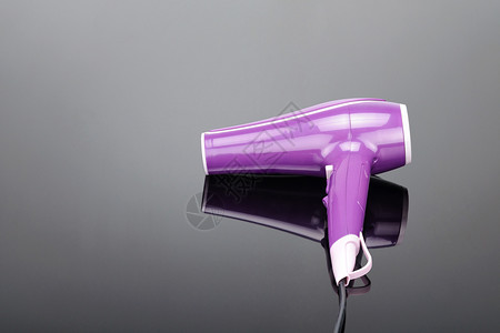 集中器头发美师型用于沙龙或理店的粉色电动手持式吹风机灰色镜面背景带复印空间灰色镜面背景上带复印空间的粉色吹风机设计图片