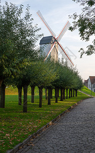 比利时布鲁日运河附近的古老风车和秋色树木布鲁日河岸附近历史景点观光图片