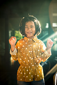 孩子女士亚裔儿童在头部电话里听到音乐的肖像微笑着快乐的情感活动图片