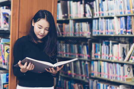 背靠书架看书的亚洲女孩图片