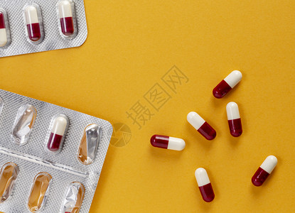 药物援助剂在黄色背景上打开片剂泡罩包装和一些红色白药用胶囊在黄色背景上打开药片和一些红色白药用胶囊背景图片