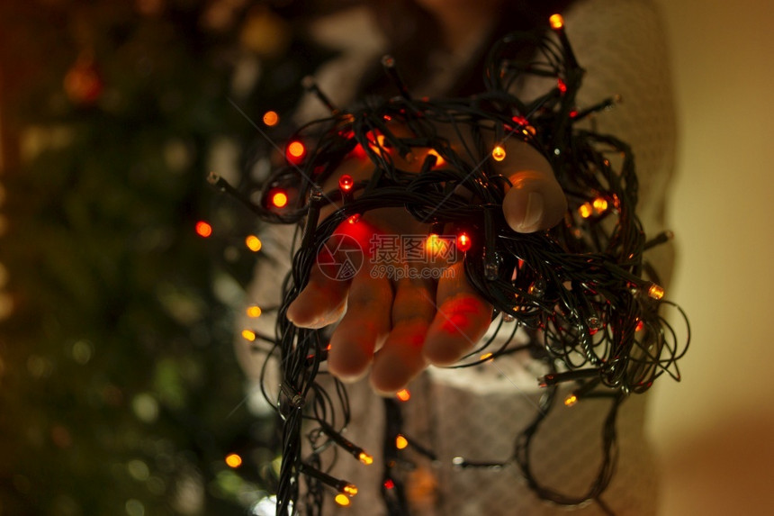 用红绿和蓝色彩灯光把女手紧贴近身以装饰圣诞树用彩灯将女手贴近衣服以装饰圣诞树有创造力的音乐氖图片