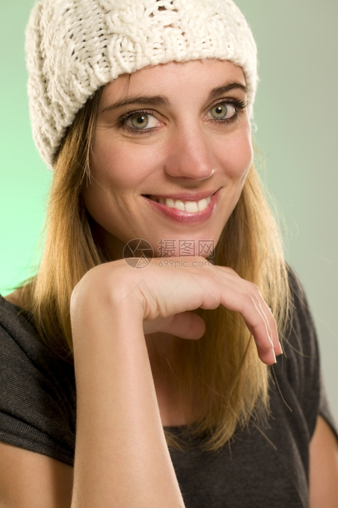 快乐的女士人们一位快乐女的肖像一位幸福女人的冬季帽肖像一位在绿色背景面前戴着冬帽的快乐女人图片