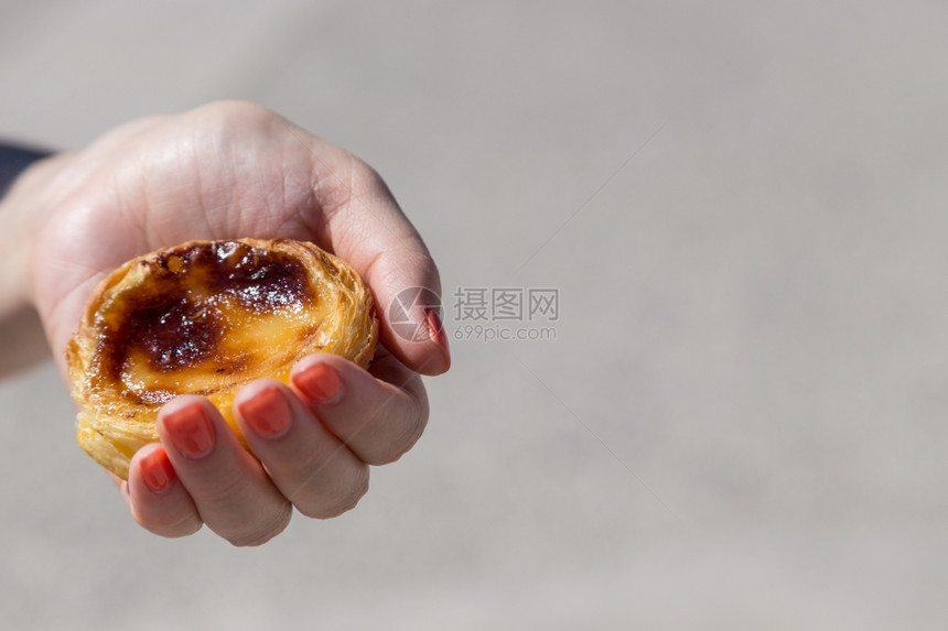 甜点在葡萄牙里斯本的背景点上葡萄牙传统妇女手中的Pasteisdenataspathesnata娜塔午餐图片